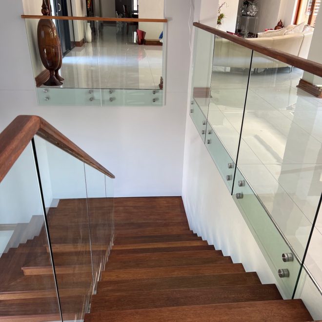 Single stringer Staircase Meranti wood threads, clear glass balustrade finished with elegant Meranti wood infills - Residential